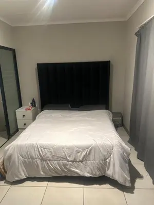 a bed with a black headboard in a bedroom at The Parks in Midrand
