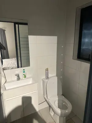 a bathroom with a toilet and a sink and a mirror at The Parks in Midrand