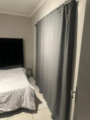 a bedroom with a bed and a gray curtain at The Parks in Midrand