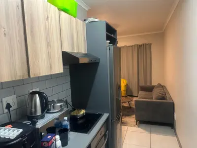 a kitchen with a stove top oven next to a couch at The Parks in Midrand