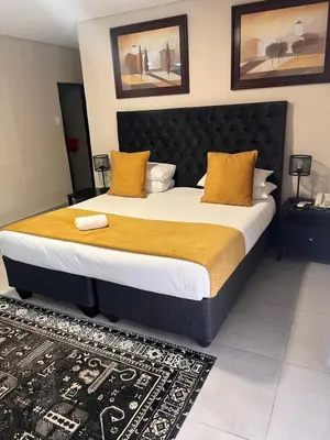a bedroom with a large bed with yellow pillows at Masana Hotels in Polokwane
