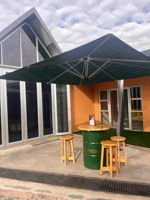 a green umbrella over a table and two stools at Masana Hotels in Polokwane