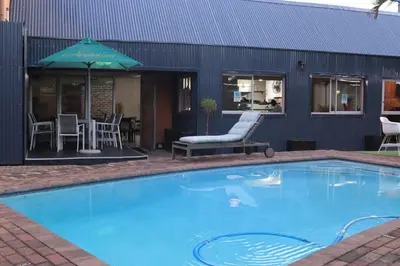 a swimming pool with a table and chairs and an umbrella at Masana Hotels in Polokwane