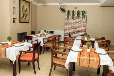 a restaurant with tables and chairs and a brick wall at Masana Hotels in Polokwane