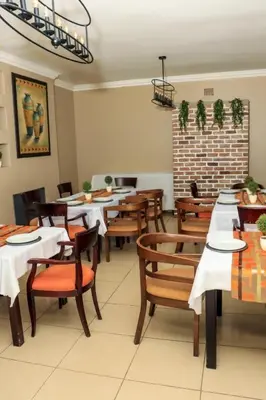 a dining room with wooden tables and chairs at Masana Hotels in Polokwane