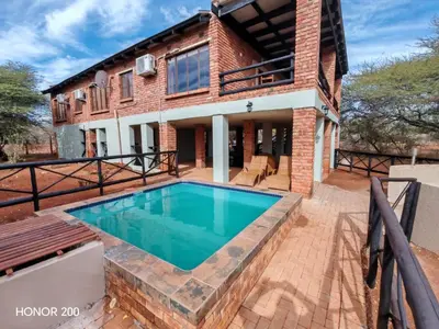 a brick house with a swimming pool in front of it at Lion's Pride - Marloth Park in Marloth Park