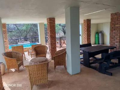 a dining room with a table and chairs and a patio at Lion's Pride - Marloth Park in Marloth Park