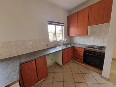 a kitchen with wooden cabinets and a sink and a stove at Midrand Apartment near Mall of Africa in Midrand