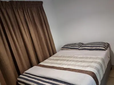 a bed with a brown curtain next to a bed sidx sidx sidx at Midrand Apartment near Mall of Africa in Midrand