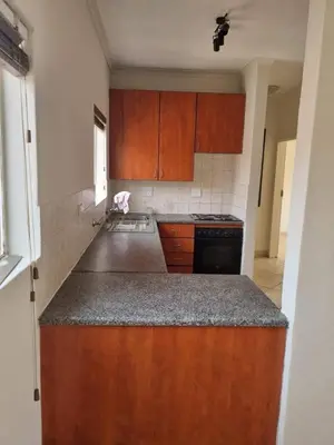 a kitchen with wooden cabinets and a counter top at Midrand Apartment near Mall of Africa in Midrand