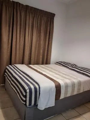 a bedroom with a bed with a striped blanket at Midrand Apartment near Mall of Africa in Midrand