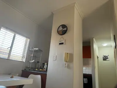 a kitchen with a clock on a wall next to a refrigerator at Midrand Apartment near Mall of Africa in Midrand