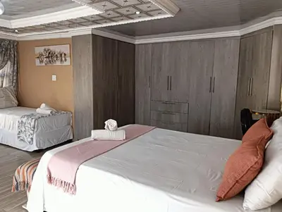 a bedroom with two beds and wooden cabinets at Newview bnb and spa in Thulamahashi