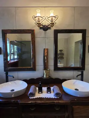 a bathroom with two sinks and two mirrors at Ukulala Inn in Malelane