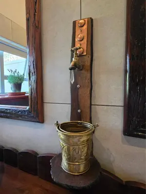 a copper bucket with a faucet on a wall at Ukulala Inn in Malelane
