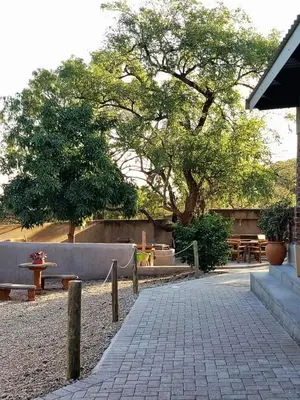 a park with benches and tables and a tree at Ukulala Inn in Malelane