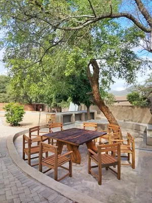 a wooden picnic table and chairs under a tree at Ukulala Inn in Malelane