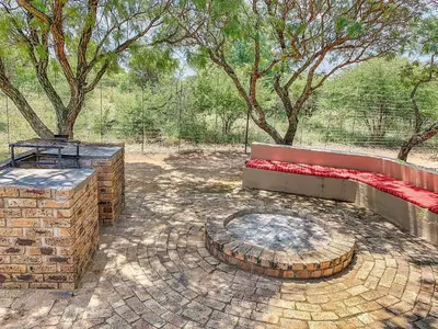 a patio with a bench and a fire pit at Tshikwalo Game Lodge in Klipdrift