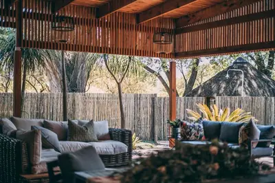 an outdoor patio with couches and a fence at Tshikwalo Game Lodge in Klipdrift