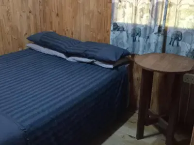 a bed with blue sheets and a table in a room at Rocky's Wildsplaas in Groblersdal