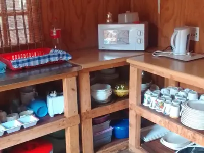 a kitchen with wooden shelves with dishes and a microwave at Rocky's Wildsplaas in Groblersdal