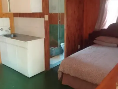 a bedroom with a bed and a bathroom with a sink at Rocky's Wildsplaas in Groblersdal