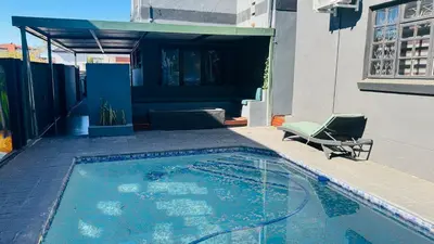 a swimming pool with a chair next to a building at Sejpro Living at 1 Motse Street in Polokwane
