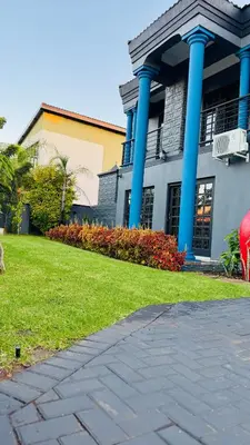 a building with blue columns and a grass yard at Sejpro Living at 1 Motse Street in Polokwane