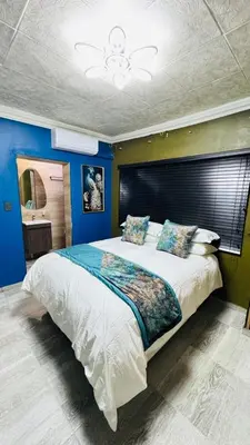 a bedroom with a large bed with blue walls at Sejpro Living at 1 Motse Street in Polokwane