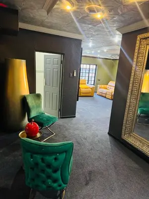 a living room with a green chair and a mirror at Sejpro Living at 1 Motse Street in Polokwane