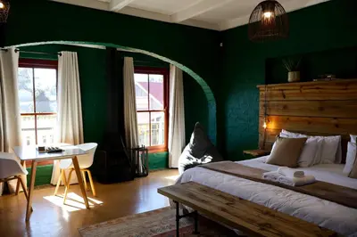 a bedroom with green walls and a bed and a table at Cherry Nest in Dullstroom