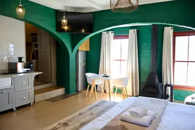 a bedroom with green walls and a table and a bed at Cherry Nest in Dullstroom