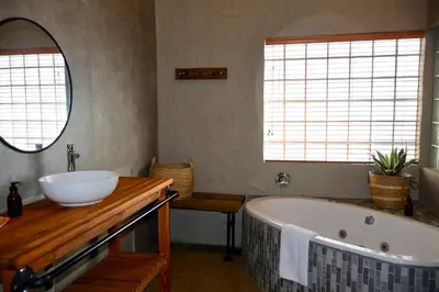 a bathroom with a tub and a sink and a mirror at Cherry Nest in Dullstroom