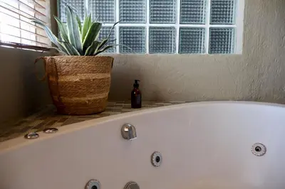 a white bath tub with a potted plant next to a window at Cherry Nest in Dullstroom