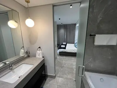 a bathroom with a sink and a shower and a bed at Hospitality at Waterfall City - Ellipse Waterfall in Midrand