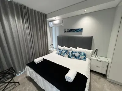 a bedroom with a bed with blue and white pillows at Hospitality at Waterfall City - Ellipse Waterfall in Midrand