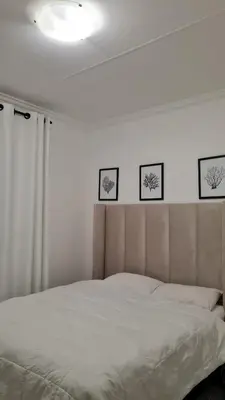 a bedroom with a white bed with three pictures on the wall at NO LOADSHEDDING 1 Bedroom Apartment in Trichardt