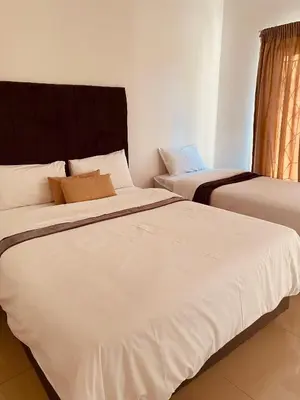 two beds in a room with white sheets at khayelihle guest house in Benoni