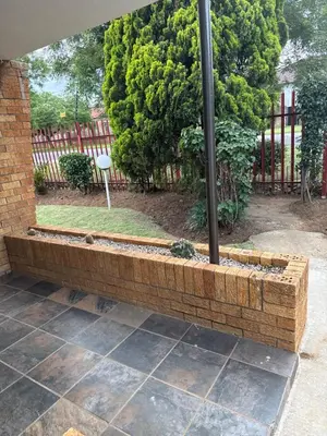 a brick retaining wall with a pole in a yard at khayelihle guest house in Benoni