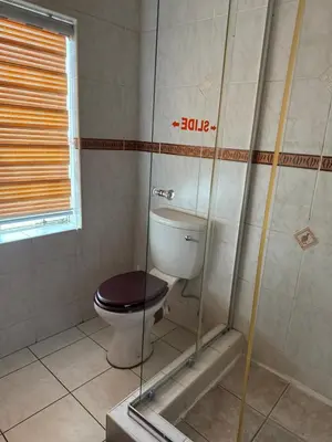 a bathroom with a toilet with a glass shower at khayelihle guest house in Benoni