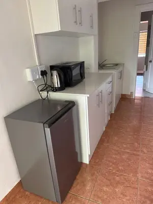 a kitchen with white cabinets and a microwave on a counter at khayelihle guest house in Benoni