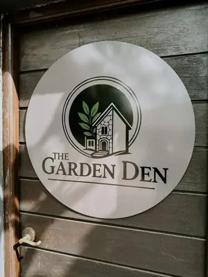 a sign for the garden den on a wooden wall at The Garden Den in Nelspruit
