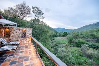 a balcony of a house with a view of the mountains at Private luxurious suite on Heysbrook Estate halfway to Kruger National Park in Waterval-Onder