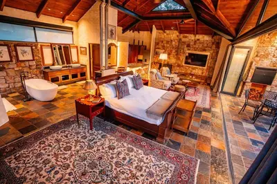 a living room with a bed and a bath tub at Private luxurious suite on Heysbrook Estate halfway to Kruger National Park in Waterval-Onder