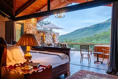 a bedroom with a bed and a balcony with a view at Private luxurious suite on Heysbrook Estate halfway to Kruger National Park in Waterval-Onder