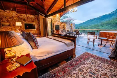 a bedroom with a bed and a balcony with a view at Private luxurious suite on Heysbrook Estate halfway to Kruger National Park in Waterval-Onder
