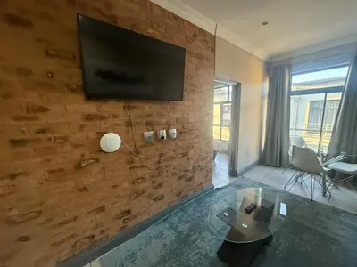 a living room with a television on a brick wall at Junction 502, Menlo Park in Pretoria