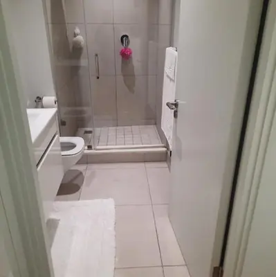 a bathroom with a shower with a toilet and a sink at Luxury Penthouse Apartment Waterfall Midrand in Midrand