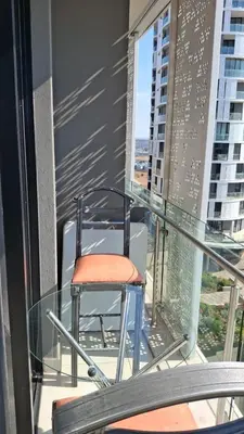 a chair sitting on a glass table on a balcony at Luxury Penthouse Apartment Waterfall Midrand in Midrand