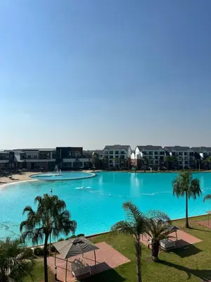 a large swimming pool with palm trees and buildings at Aesthetic Luxury 2 bedroom penthouse in Pretoria